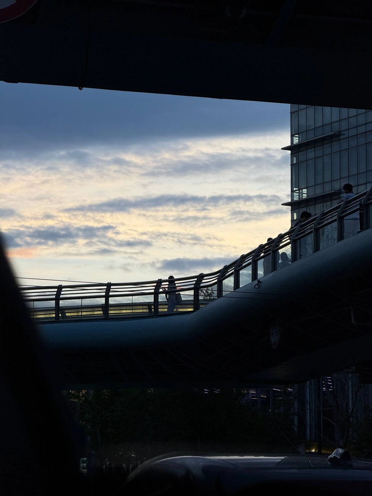 Silhouetted pedestrians crossing a footbridge at dusk
