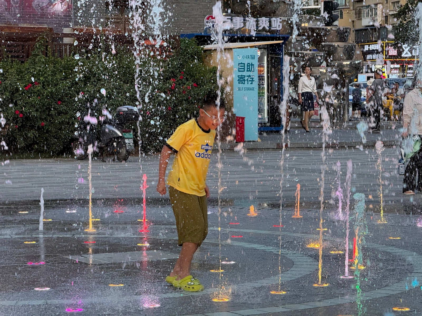 A child playing among colorful ground fountains