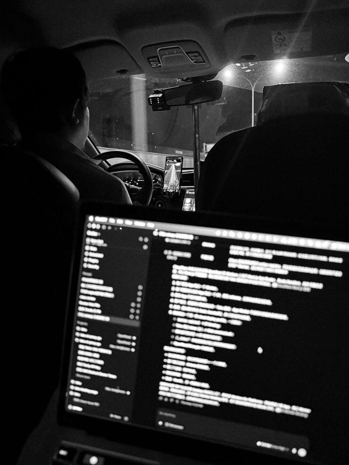 A laptop displaying code in the back seat of a car at night