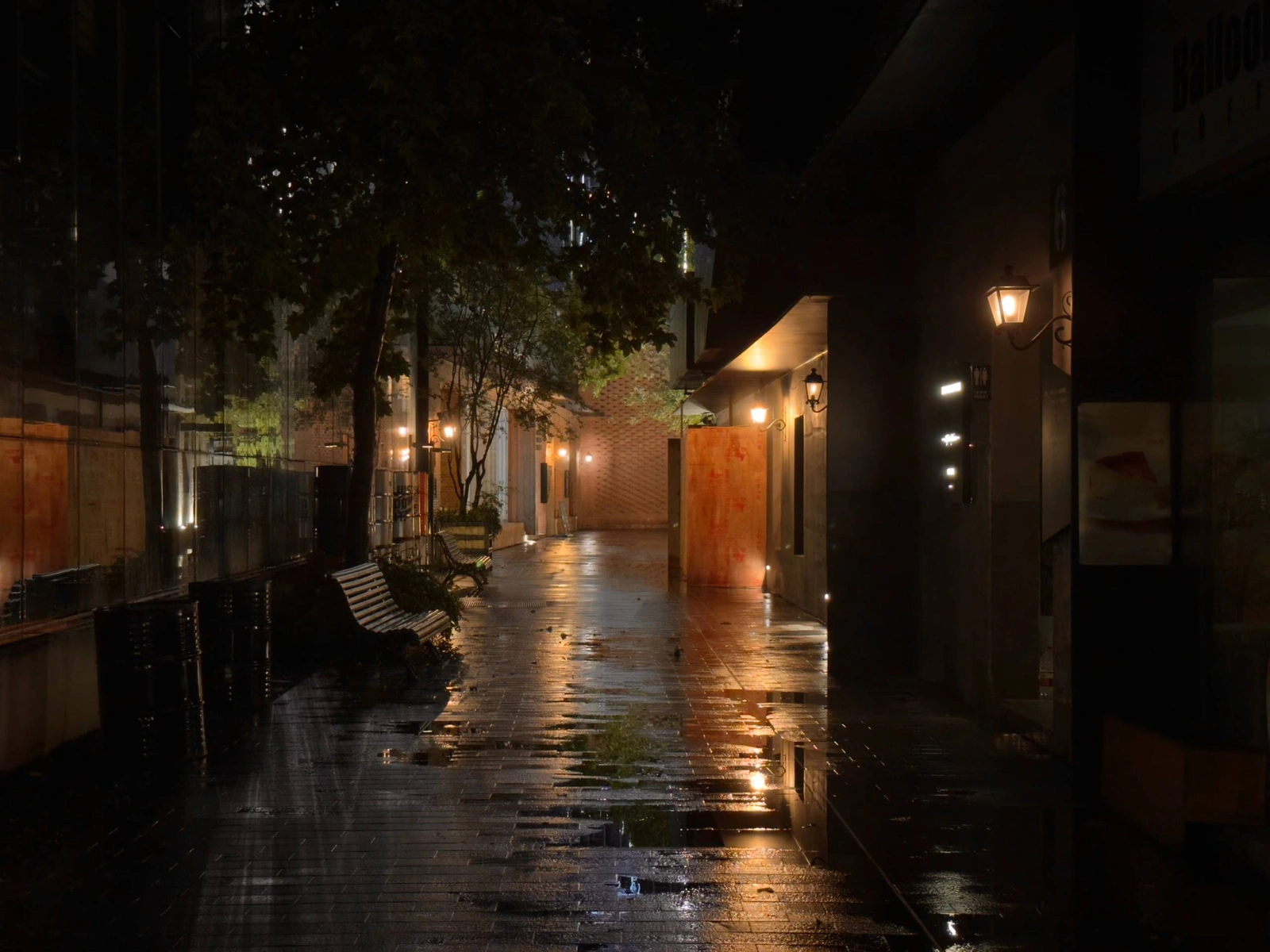 Warm streetlights reflected on a rain-soaked walkway at night